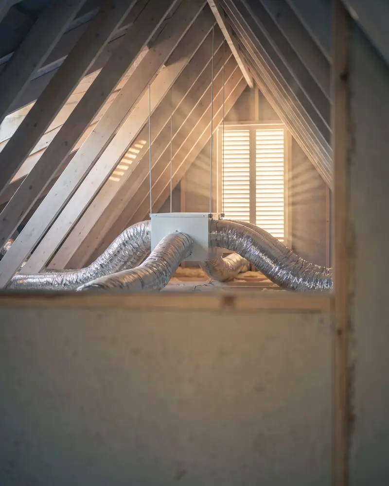 Insulated flexible ducts running from a supply plenum in a tidy, sunlit attic
